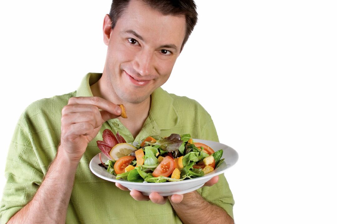 Mann isst Gemüsesalat, um aufzuladen